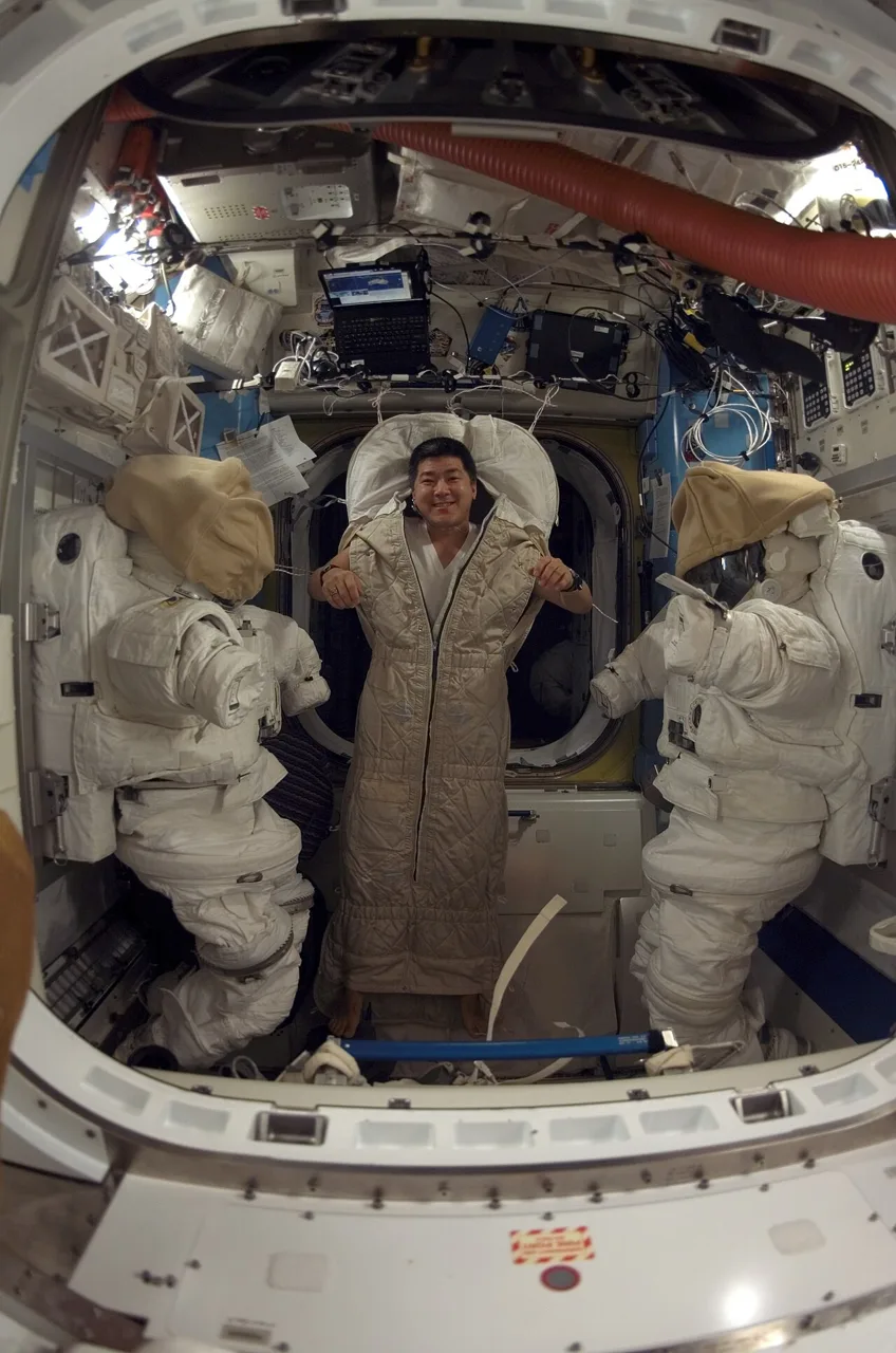 An astronaut in a sleeping bag inside the International Space Station.